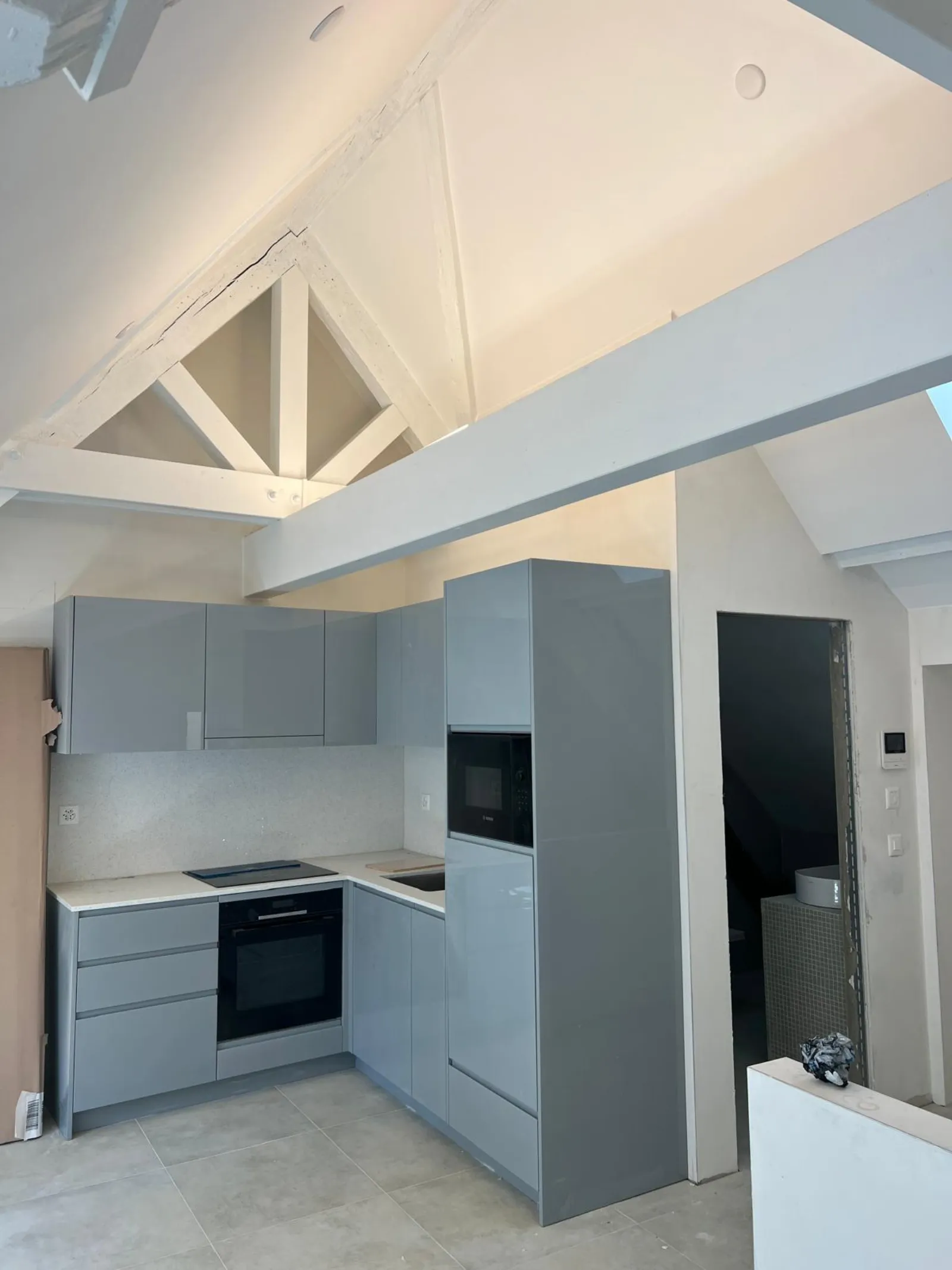 Cuisine grise mansardée sous toiture après rénovation des combles