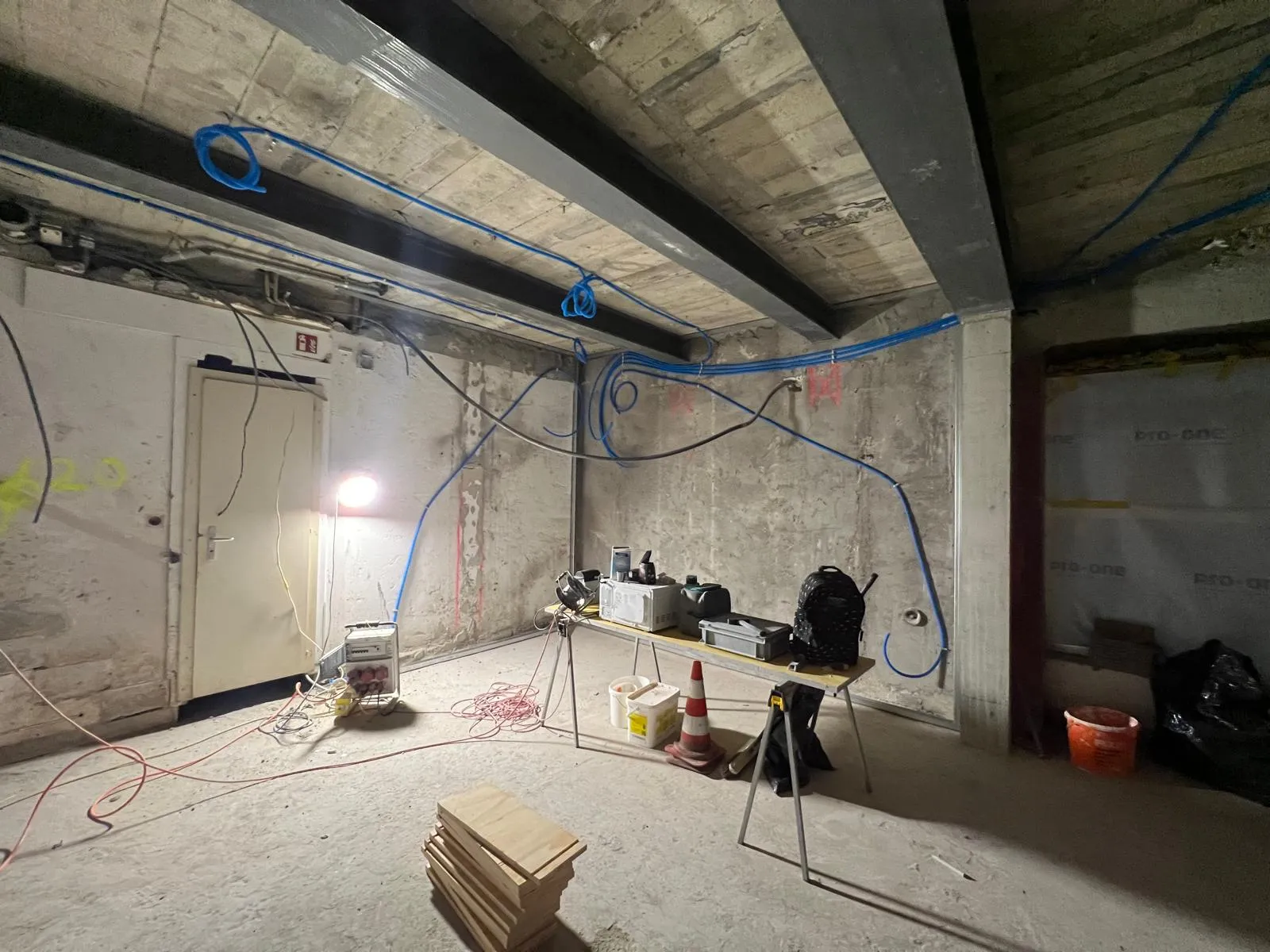 Sous-sol béton avec gaines électriques bleues pendant rénovation