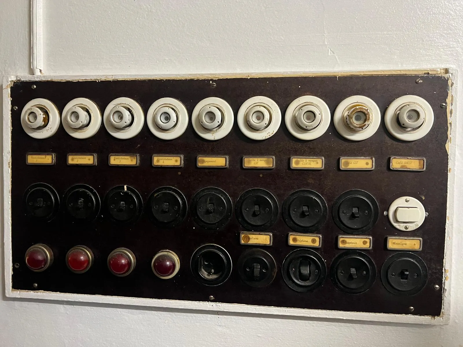 Ancien tableau de commande à boutons bakélite et lampes témoins rouges du restaurant