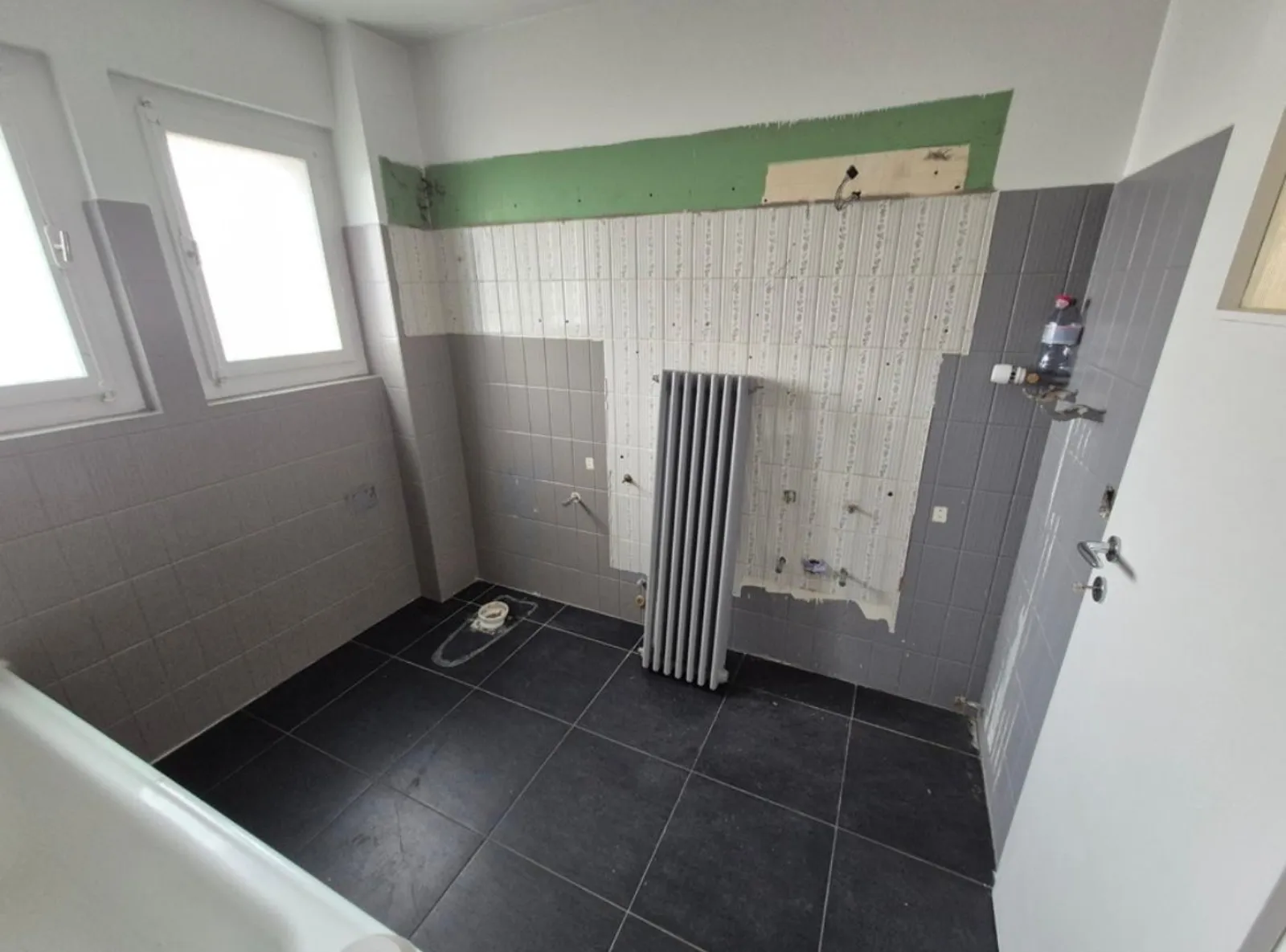Salle de bain en cours de dépose, anciens carrelages et radiateur démonté